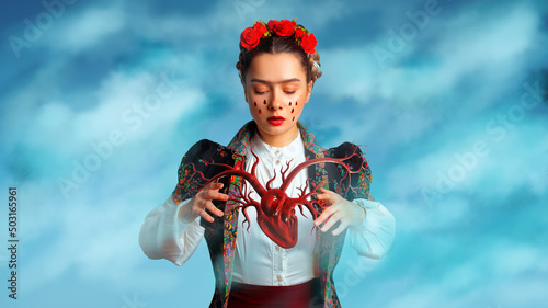 A young woman in the image of Frida supports her heart. Heart and soul of a creative person, a young woman photo