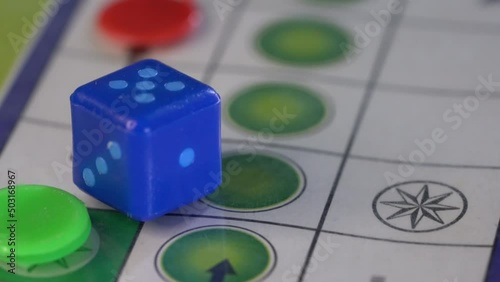 Blue dice on a Ludo board game. 