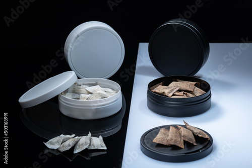 Closeup of two Swedish smokeless tobacco products. Snus cans with white and regular portion snuff
