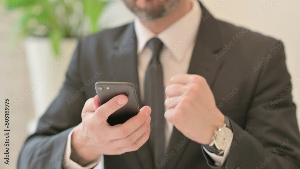 Close up of Middle Aged Businessman Celebrating Success on Smartphone Close up of Middle Aged Businessman Celebrating Success on Smartphone