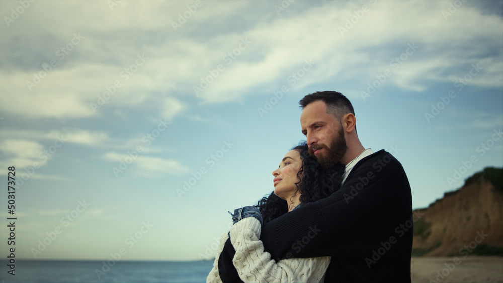 Relaxed couple cuddling together on beach vacation. Lovers relaxing at shoreline