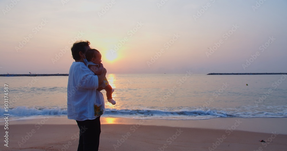 happiness Asian family grandmother is keeping on her arms holding cute adorable newborn baby infant girl on a seaside tropical beach at sunrise morning during holiday vacation in Thailand
happiness Asian family grandmother is keeping on her arms holding cute adorable newborn baby infant girl on a seaside tropical beach at sunrise morning during holiday vacation in Thailand