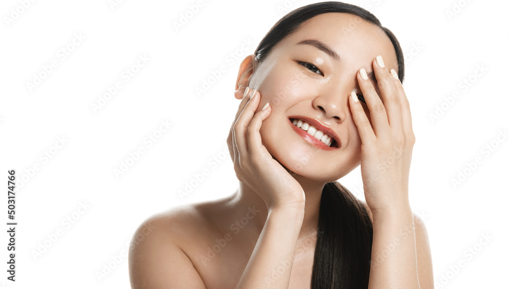 Clear skin. Beautiful young asian girl touches perfect smooth face without blemishes, smiles with white healthy teeth, stands over white background Clear skin. Beautiful young asian girl touches perfect smooth face without blemishes, smiles with white healthy teeth, stands over white background