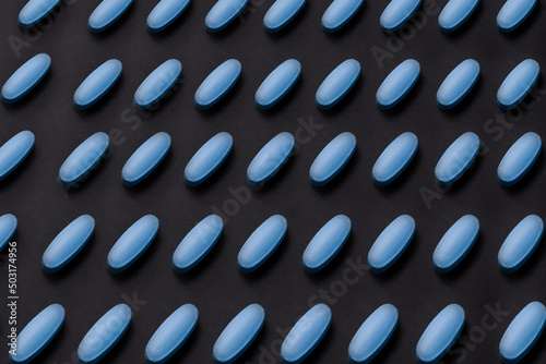 Ordered pattern of blue tablets on black background