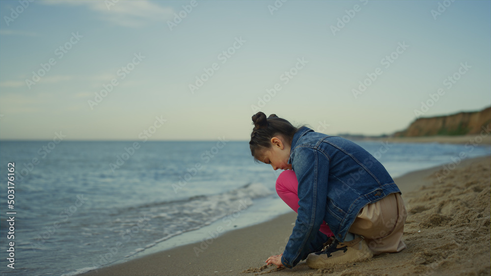 Child playing beach sand at sea family trip. Small girl spend time alone outside Child playing beach sand at sea family trip. Small girl spend time alone outside