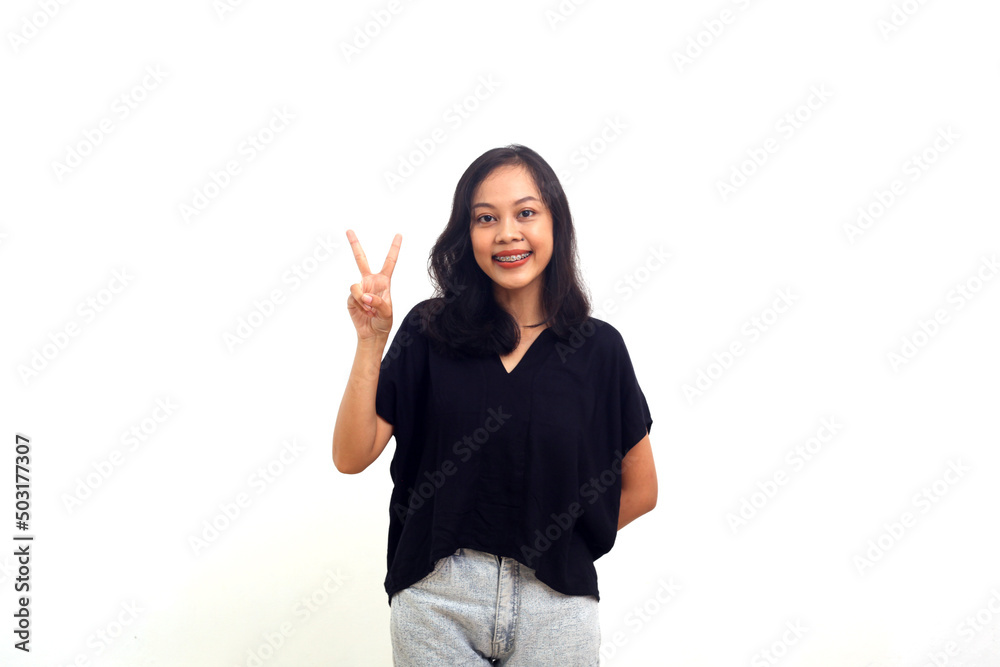 Photo of cheerful asian girl happy positive smile show peace sign isolated over white background Photo of cheerful asian girl happy positive smile show peace sign isolated over white background