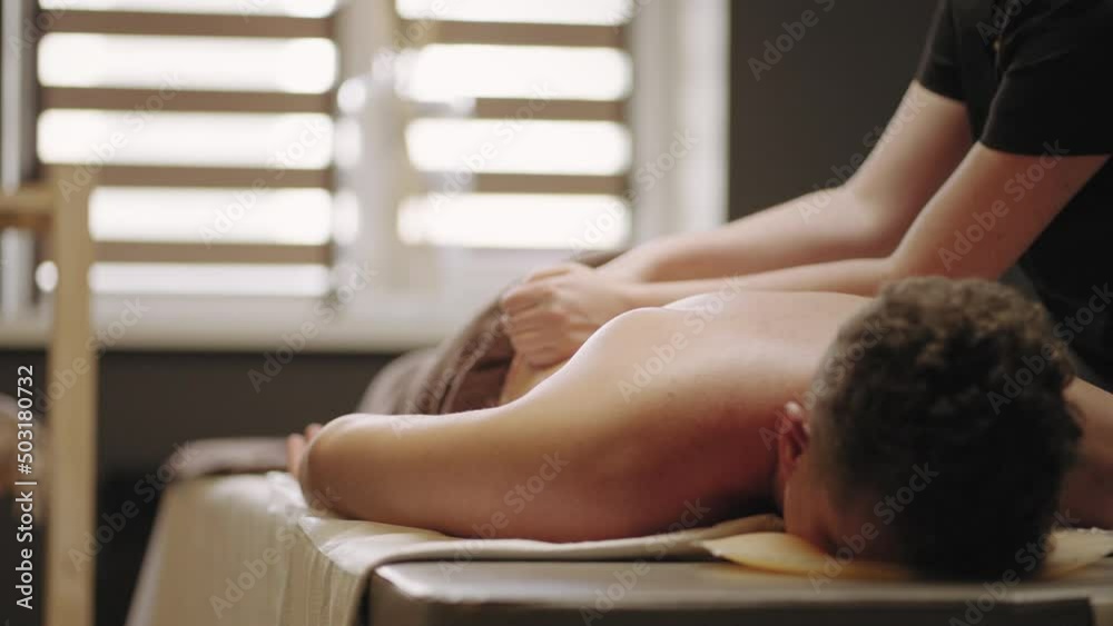relax massage in osteopathic clinic, man is lying n professional coach and masseuse is massaging his back relax massage in osteopathic clinic, man is lying n professional coach and masseuse is massaging his back