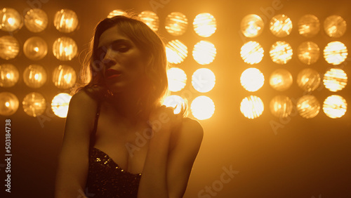 Beautiful woman dancing sexually alone in night club spotlights.