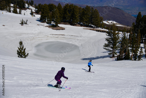 Skiing downhill on a beautiful sunny day at Snowbasin Ski Resort, Utah. Spring conditions in mountains, April month. photo