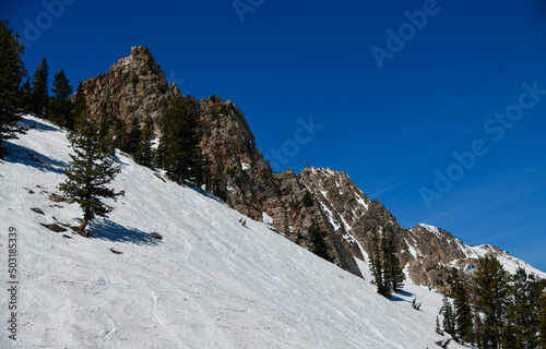 Beautiful landscape at Snowbasin Ski Resort, Utah. Snow slopes, rocky mountains and trees on a sunny day.
