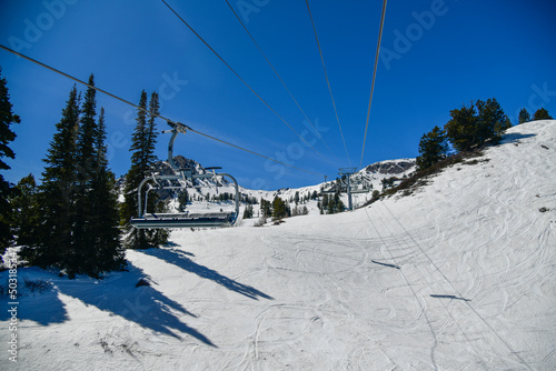 Chair lift going up at the Snowbasin Ski Resort in Utah. Ski vacation in early spring season.