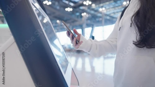 Passenger using smartphone scanning qr code on the ticket machine to check in for the flight at the airport terminal, less contact new normal technology, Screen scanner redeem ticket, online booking