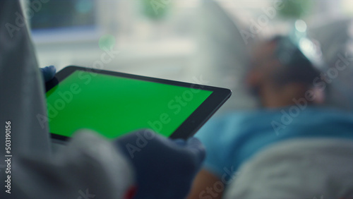 Doctor using pad chroma key screen closeup. Patient oxygen mask in hospital bed