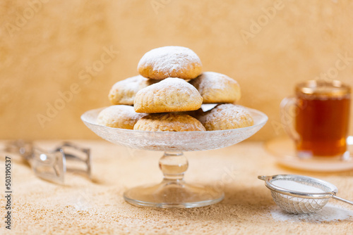 traditional Islamic Feast,Cookies for celebration of Eid El Fitr (Kahk) dusted with fine sugar with a cub of tea in the background  photo