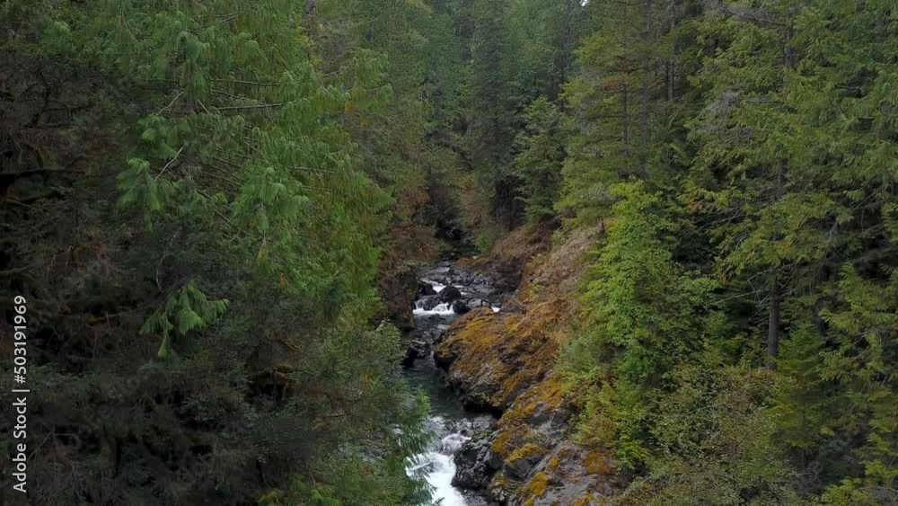 Aerial ascending and revealing river flowing through rocky terrain in the forest. Aerial ascending and revealing river flowing through rocky terrain in the forest.