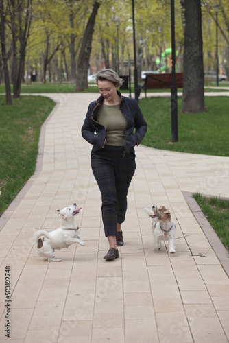 Woman walking in the park with two jack russell terriers