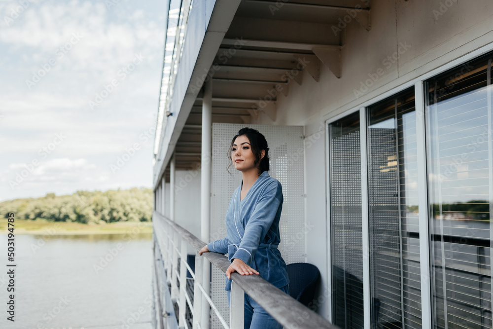 Woman in the city on the balcony. Girl at the window of his apartment in the city. Lady on the background of the city river.