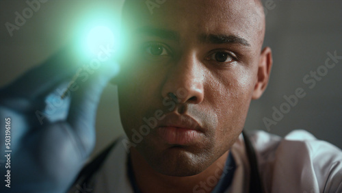 Portrait african american therapist checking light reaction in clinic ward.