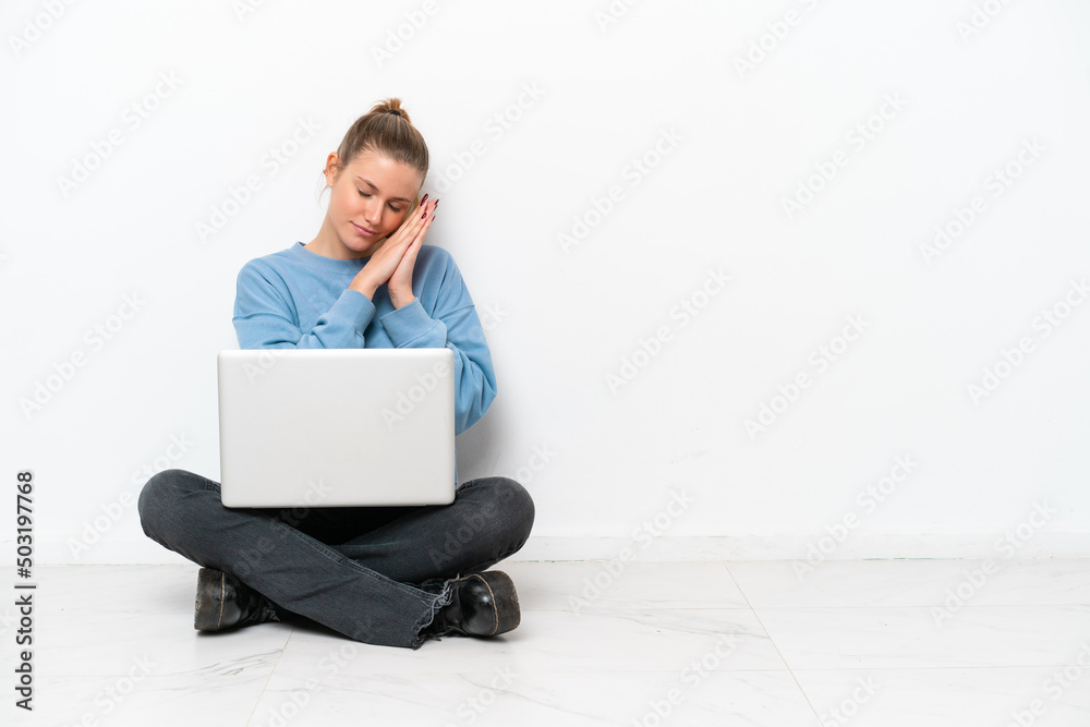 Young woman with a laptop sitting on the floor making sleep gesture in dorable expression Young woman with a laptop sitting on the floor making sleep gesture in dorable expression