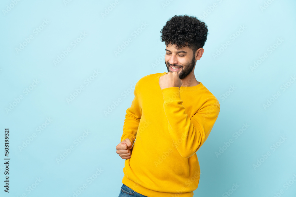 Young Moroccan man isolated on blue background celebrating a victory Young Moroccan man isolated on blue background celebrating a victory