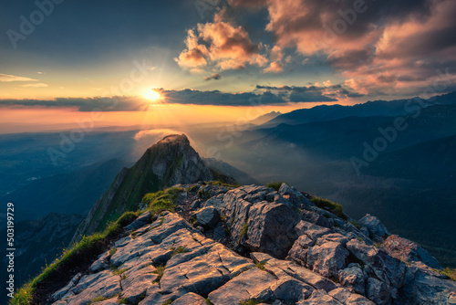 Fototapeta Naklejka Na Ścianę i Meble -  Cloudy, spectacular sunrise view on the top of the rocky Giewont peak of Tatry mountains. Landscape in nature with stones in the foreground.