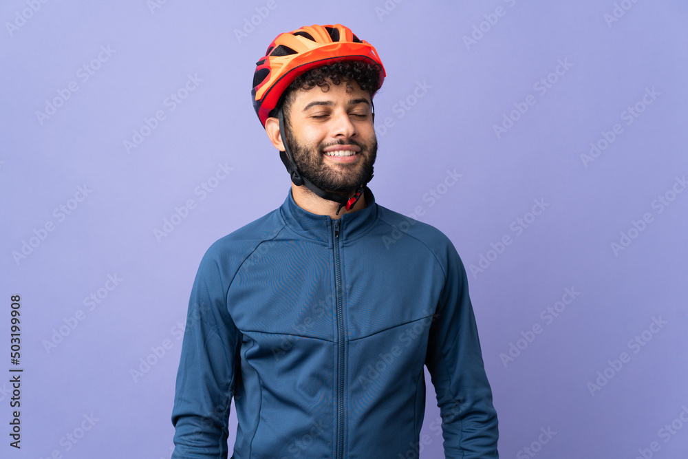 Young Moroccan cyclist man isolated on purple background laughing - obrazy, fototapety, plakaty 