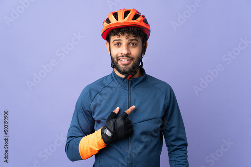 Young Moroccan cyclist man isolated on purple background with surprise facial expression