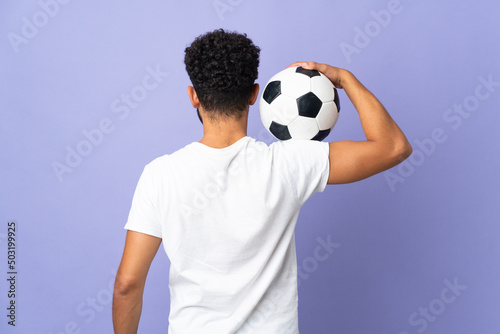 Young Moroccan man isolated on purple background with soccer ball