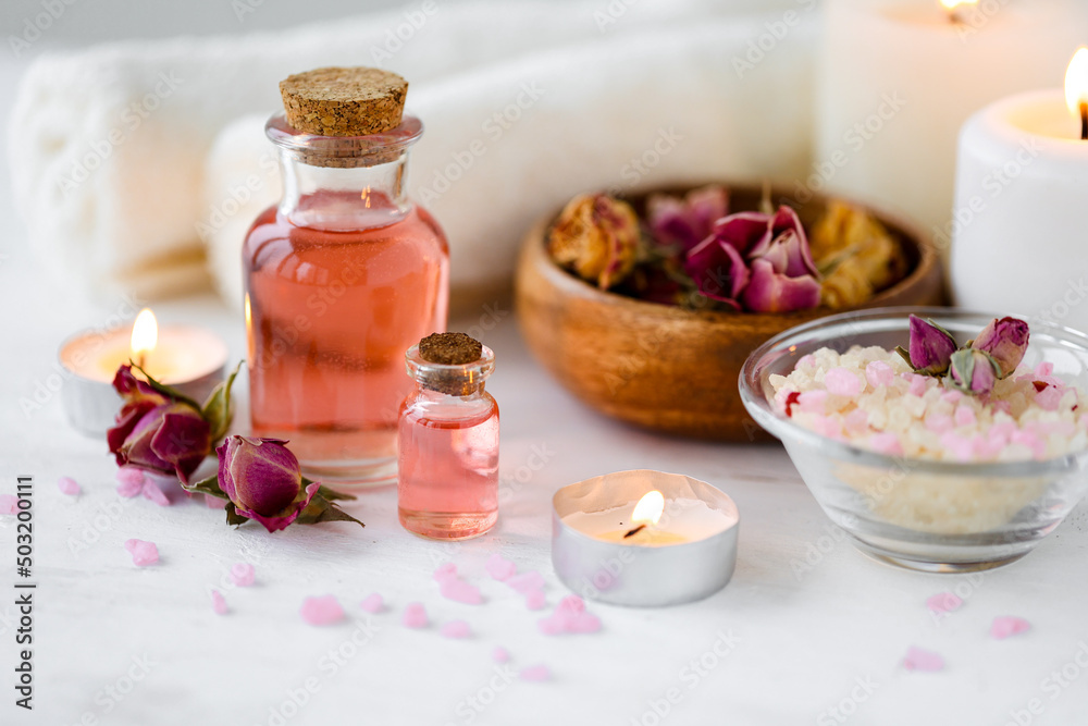 Concept of spa treatment in salon. Natural organic oil, towel, candles as decor. Atmosphere of relax, serenity and pleasure. Anti-stress and detox procedure. Luxury lifestyle. White wooden background Concept of spa treatment in salon. Natural organic oil, towel, candles as decor. Atmosphere of relax, serenity and pleasure. Anti-stress and detox procedure. Luxury lifestyle. White wooden background