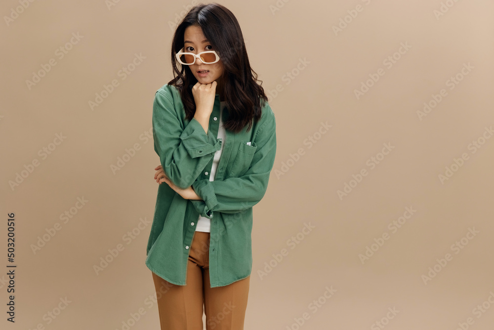 Oops. Upset pensive cute Korean young woman in khaki green shirt stylish eyewear recline on fist posing isolated on over beige pastel studio background. Cool fashion offer. Sunglasses ad concept Oops. Upset pensive cute Korean young woman in khaki green shirt stylish eyewear recline on fist posing isolated on over beige pastel studio background. Cool fashion offer. Sunglasses ad concept