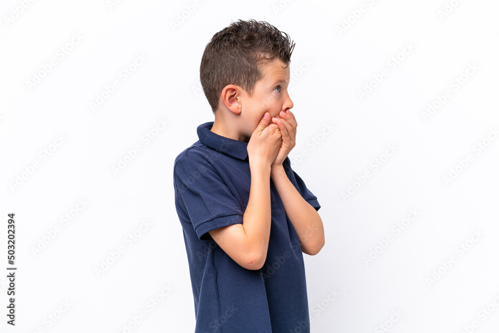 Little caucasian boy isolated on white background covering mouth and looking to the side Little caucasian boy isolated on white background covering mouth and looking to the side
