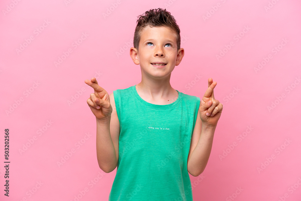 Little caucasian boy isolated on pink background with fingers crossing and wishing the best Little caucasian boy isolated on pink background with fingers crossing and wishing the best