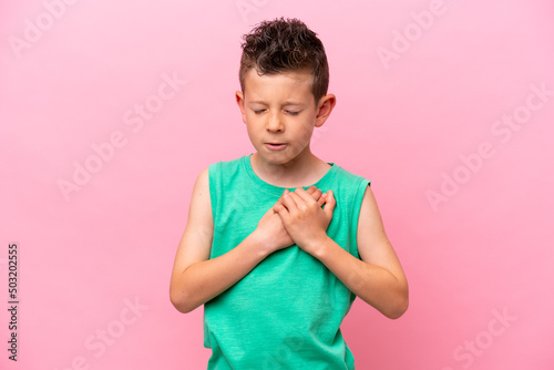 Little caucasian boy isolated on pink background having a pain in the heart