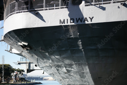 The USS Midway on the San Diego Embarcadero with the Welcome Home Kissing Sailor Staute in View below the Stern photo