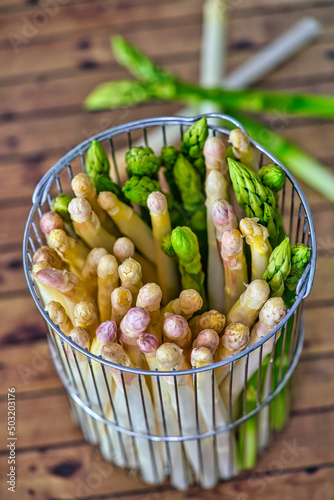 Spring season, new harvest of German white and green asparagus, bunch of raw green and white asparagus in basket with background of wood