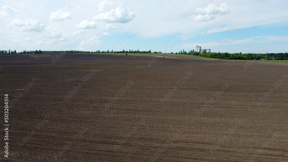 Aerial drone view flight over huge plowed field and blue sky. Skyline, horizon. Black earth. Agriculture, agricultural activities. Rural country landscape. Digging up the earth. Agronomy, farmin