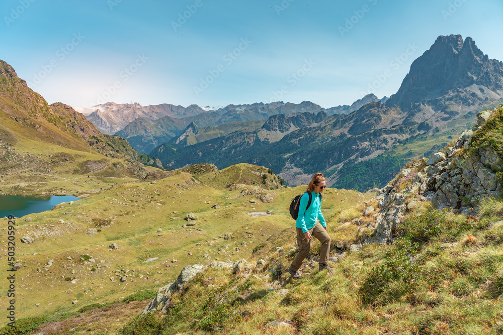 Young Attractive Woman With A Backpack hiking in a beautiful valley between mountains during the sunset. Discovery Travel Destination Concept