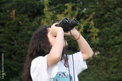 Young girl is discovering the surrouding she is looking through a binocular. photo