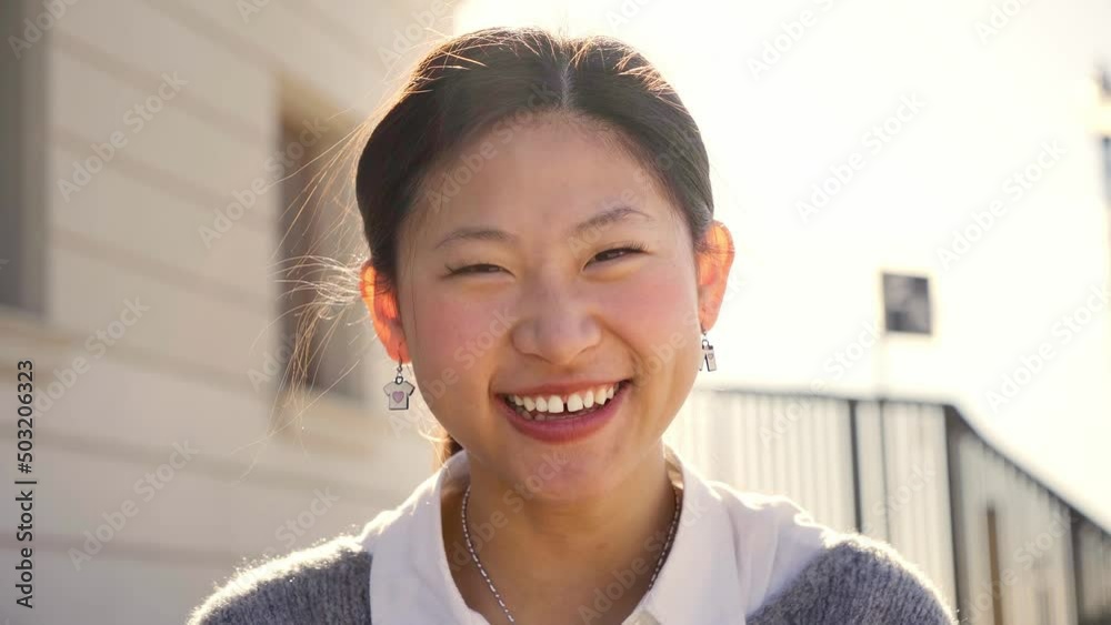 Outdoor portrait of a smiling Chinese girl looking at the camera laughing with positive face and friendly look. Close up of a Happy human face - Cheerful Asian girl. Concept of people and emotions.