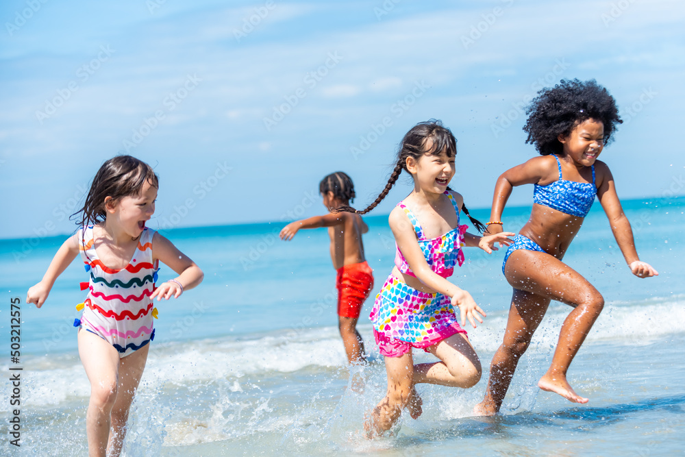 Group of Diversity little child boy and girl friends running and playing in sea water on tropical beach together on summer vacation. Happy children kid enjoy and fun outdoor lifestyle on beach holiday Group of Diversity little child boy and girl friends running and playing in sea water on tropical beach together on summer vacation. Happy children kid enjoy and fun outdoor lifestyle on beach holiday