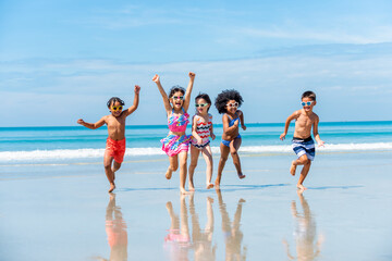 Group of Diversity little child boy and girl friends running and playing in sea water on tropical beach together on summer vacation. Happy children kid enjoy and fun outdoor lifestyle on beach holiday
