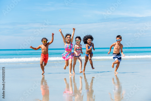 Group of Diversity little child boy and girl friends running and playing in sea water on tropical beach together on summer vacation. Happy children kid enjoy and fun outdoor lifestyle on beach holiday
