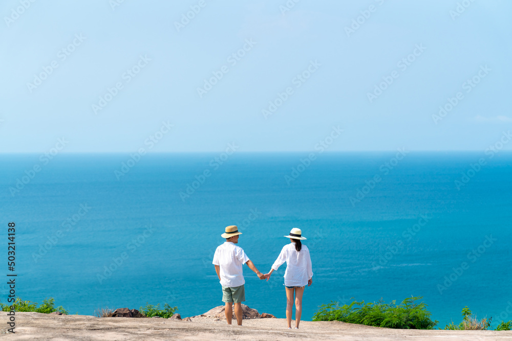  Happy Asian family couple holding hands and walking together while travel on tropical island mountain in summer sunny day. Husband and wife enjoy outdoor activity lifestyle holiday travel vacation