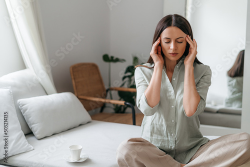 Young woman with headache in home interior photo