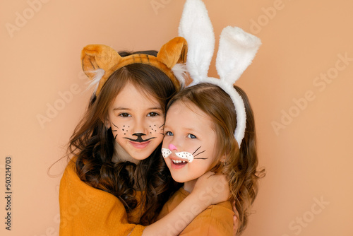 Kids with painted faces in guise of rabbit and tiger. Zodiac 2023 year according to Chinese calendar. Girl dressed up with bunny ears and makeup in anticipation new year. Symbol outgoing old year 2022