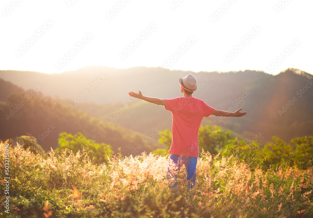 Man with arms raised with sunset in the mountains in the background. Man praying and thanking God outdoors. Success, happiness and well being. concept. Man with arms raised with sunset in the mountains in the background. Man praying and thanking God outdoors. Success, happiness and well being. concept.