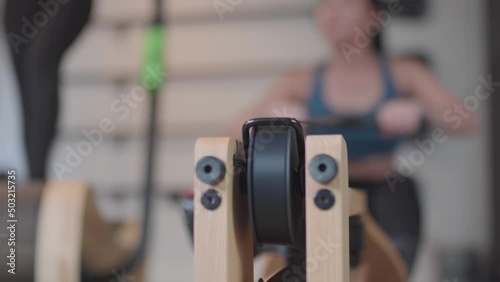 Two fit girls exercising on fancy equipment in modern fitness center. Tredmill and water resistance rowing machine.. photo