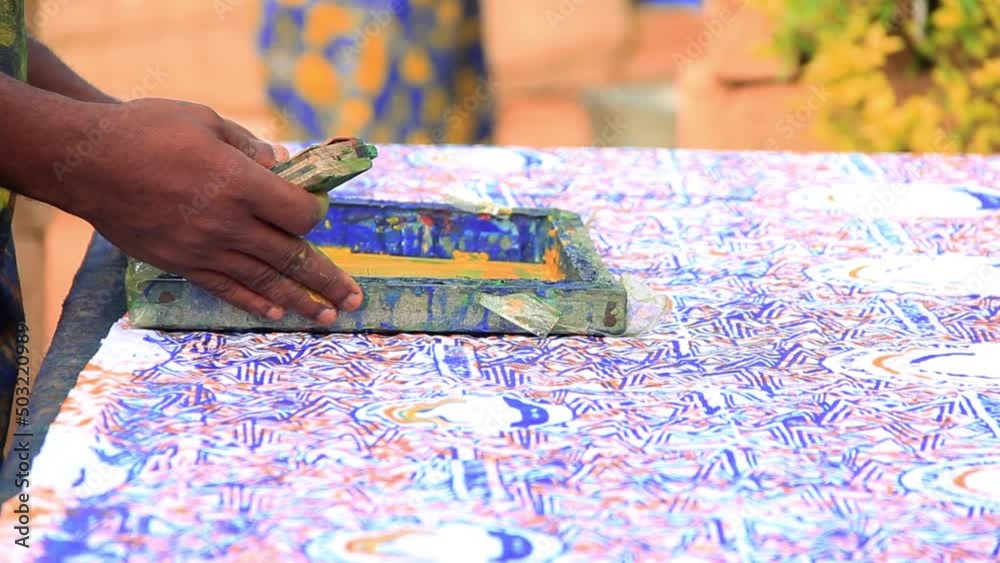 Hand printing African cloth with wooden screen printing machine. Hand printing African cloth with wooden screen printing machine.