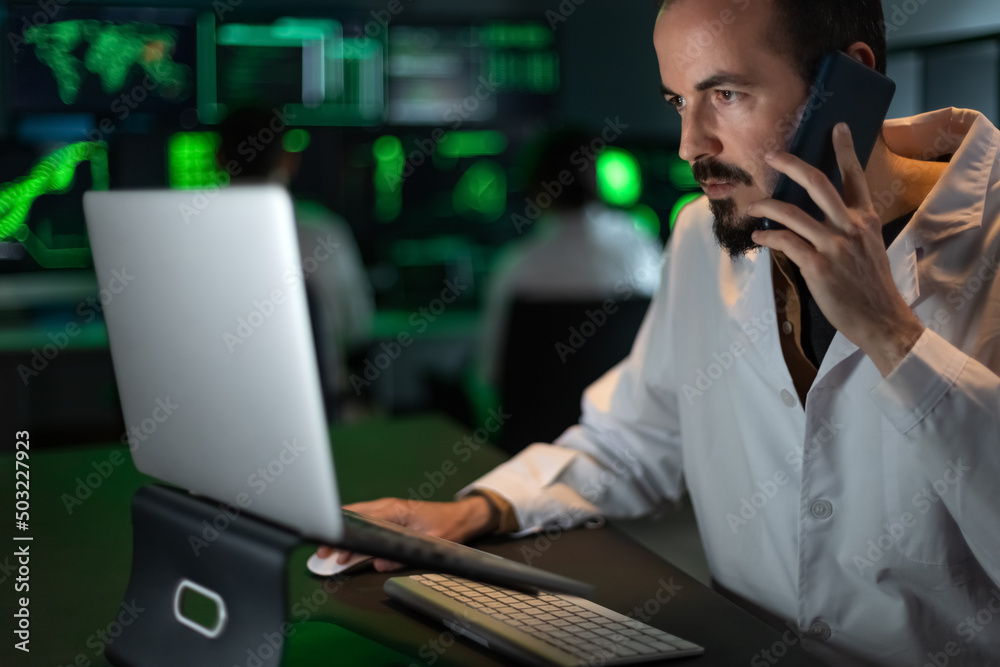 Caucasian male scientist doctor working in the lab using laptop and talking on the phone. Caucasian male scientist doctor working in the lab using laptop and talking on the phone.