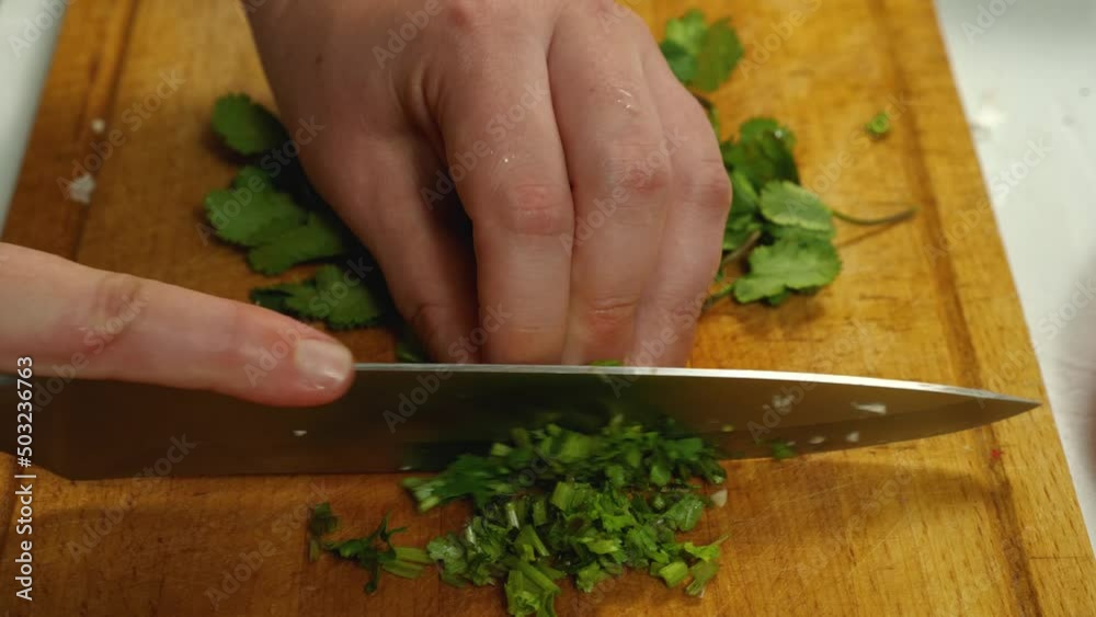 Close-up of a cook slicing parsley. Side view from above. A vegetarian kitchen. The concept of delicious and healthy food Close-up of a cook slicing parsley. Side view from above. A vegetarian kitchen. The concept of delicious and healthy food